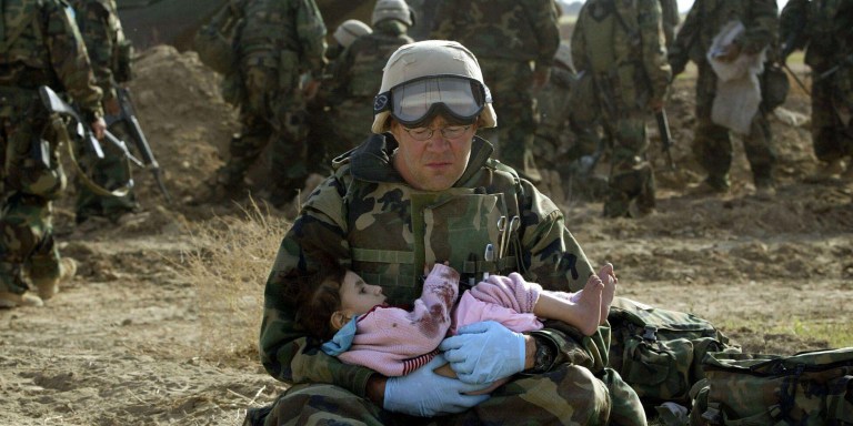 2D3XN9W A U.S. marine doctor holds an Iraqi girl in central Iraq March 29, 2003. Confused front line crossfire ripped apart an Iraqi family on Saturday after local soldiers appeared to force civilians towards U.S. marines positions.