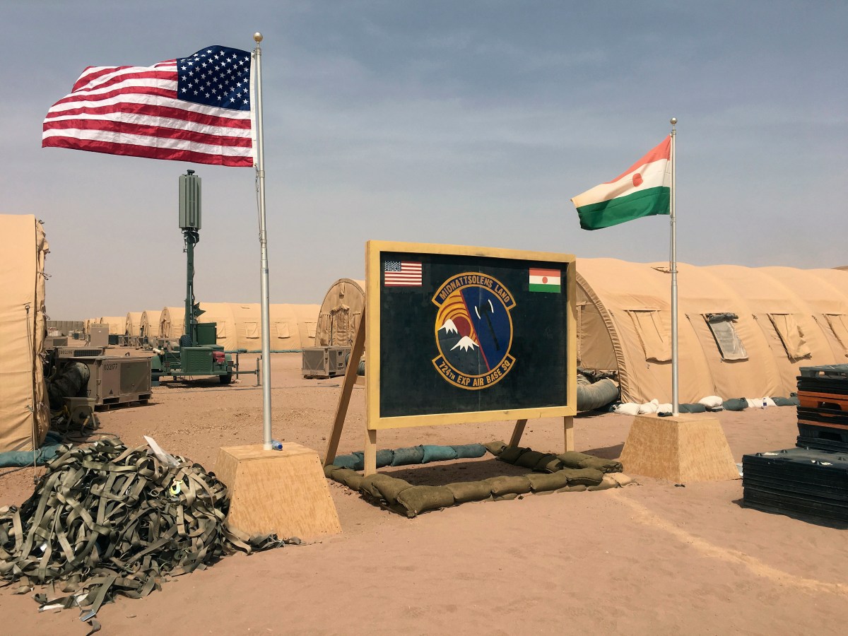 FILE- In this file photo taken Monday, April 16, 2018, a U.S. and Niger flag are raised side by side at the base camp for air forces and other personnel supporting the construction of Niger Air Base 201 in Agadez, Niger. As extremist violence grows across Africa, the United States is considering reducing its military presence on the continent, a move that worries its international partners who are working to strengthen the fight in the tumultuous Sahel region. (AP Photo/Carley Petesch, File)