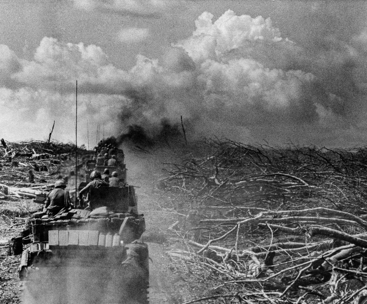 Under white-capped clouds, a column of tanks and armored personnel carriers of the U.S. 11th armored regiment moves through the Snoul rubber plantation inside Cambodia toward the Snoul airfield where heavy North Vietnamese resistance was encountered, May 12, 1970. The plantation land had been cleared before the operation began and trees shown here were not demolished by tanks. (AP Photo)