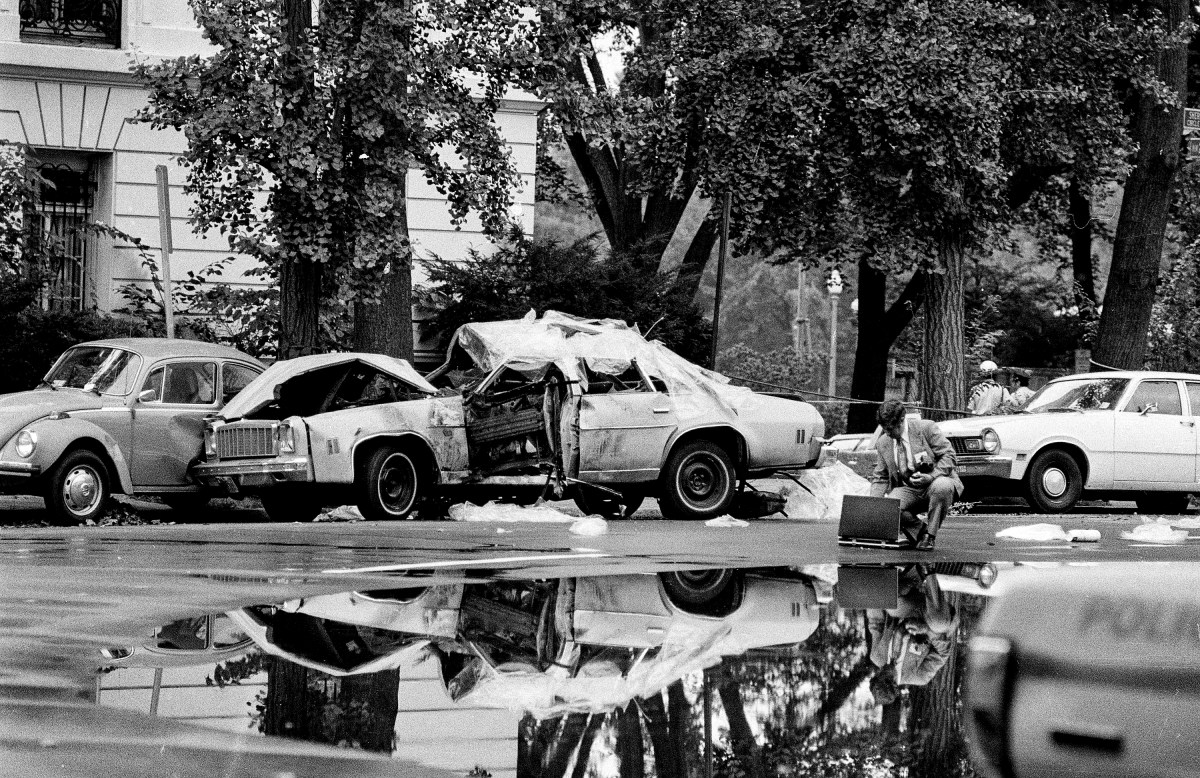A car that was carrying three persons is covered with a protective material as police investigators probe the cause of a blast that killed two persons riding in the car and seriously injured one other, Sept. 21, 1976, in upper northwest Washington, D.C. Police say the car was registered to Orlando Letelier, 44, former Chilean ambassador to the U.S. during the Allende regime. Names of victims are being withheld.  (AP Photo/Peter Bregg)