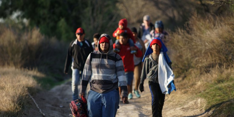 Central American migrants walk along the Mexican bank of the Rio Bravo that divides the cities of Eagle Pass, in Texas, US and Piedras Negras, in the state of Coahuila, Mexico on February 17, 2019. - Last week Trump invoked a "national emergency" to justify tapping military and other funds for barrier construction, after Congress approved less than a fourth the $5.7 billion he had sought for border security. A White House top adviser said Sunday that the president's emergency declaration could allow "hundreds of miles" of barriers to be built on the Mexican border before the 2020 election. (Photo by Julio Cesar AGUILAR / AFP)        (Photo credit should read JULIO CESAR AGUILAR/AFP via Getty Images)