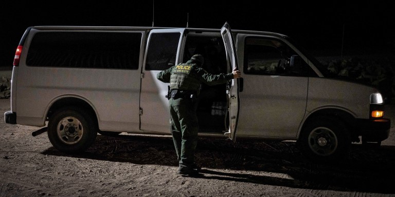 A US Customs and Border Patrol agent closes the doors to a van carrying asylum-seekers at the US-Mexico border fence near Somerton, Arizona, on December 26, 2022. - The United States is seeing a rising number of asylum-seekers turning themselves in at the US-Mexico border in anticipation of the lifting of Title 42, a pandemic-era policy used to bar migrants from entering the US. (Photo by Rebecca NOBLE / AFP) (Photo by REBECCA NOBLE/AFP via Getty Images)