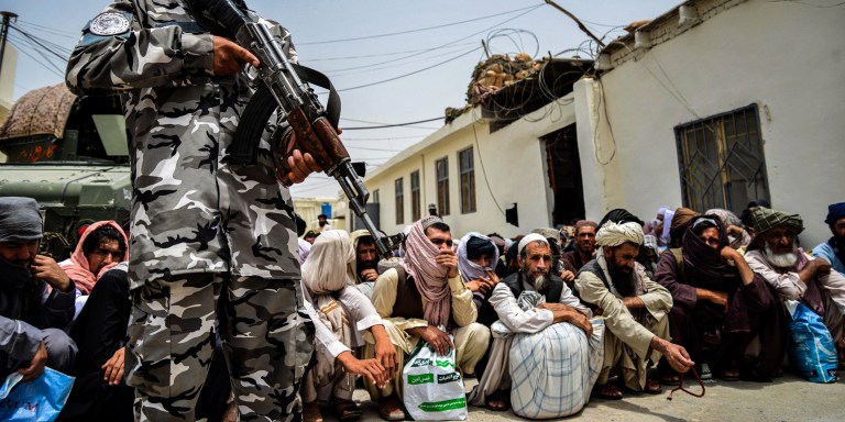 A Taliban scurity personnel stands guard next to prisioners waiting for their release from the central prison in Kandahar on June 27, 2023. (Photo by Sanaullah SEIAM / AFP) (Photo by SANAULLAH SEIAM/AFP via Getty Images)