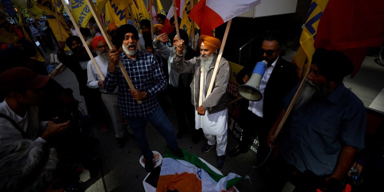 People stomp on an Indian flag and a cutout of Indian prime minister Narendra Modi during a Sikh rally outside the Indian consulate in Toronto to raise awareness for the Indian government's alleged involvement in the killing of Sikh separatist Hardeep Singh Nijjar in British Columbia on September 25, 2023. Prime Minister Justin Trudeau's assertion on September 17, 2023 that agents linked to New Delhi may have been responsible for the June 18 murder of Hardeep Singh Nijjar, a Canadian citizen, sent shockwaves through both countries, prompting the reciprocal expulsion of diplomats. (Photo by Cole BURSTON / AFP) (Photo by COLE BURSTON/AFP via Getty Images)