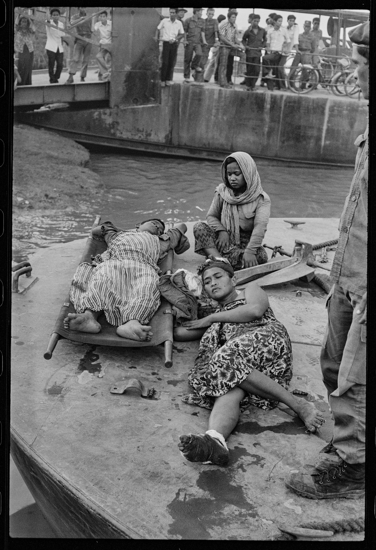 (Original Caption) Victims of U.S. Bombing Error. Phnom Penh: Cambodian civilians wounded in bombing error by U.S. warplanes at Neak Luong August 6, await transportation to hospital after having been brought here by Navy boats August 7. It's estimated some 300 civilian and military persons were killed or wounded in the attack.