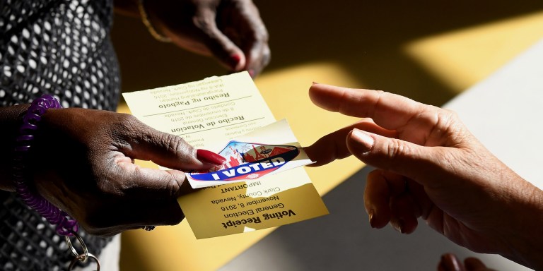 NORTH LAS VEGAS, NV - NOVEMBER 08:  A poll worker gives a voter a Las Vegas Strip-themed "I Voted" sticker after taking back her voter activation card at a polling station at Cheyenne High School on Election Day on November 8, 2016 in North Las Vegas, Nevada. Americans across the nation are picking their choice for the next president of the United States.  (Photo by Ethan Miller/Getty Images)